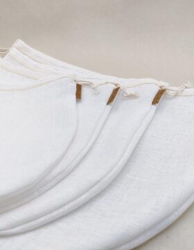 Die vier unterschiedlich großen weißen Leinenfilterbeutel liegen aufgereiht, das braune Nectarbar Etikett ist gut sichtbar.